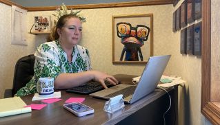 A Woman Reading a Book while Sitting Beside the Man in Blue Sweater